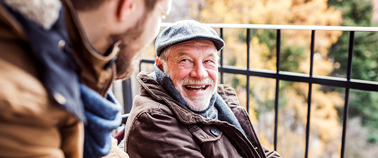 Older man laughing with his son outside