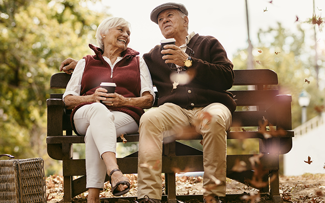 Senior couple sitting on bench and drinking coffees